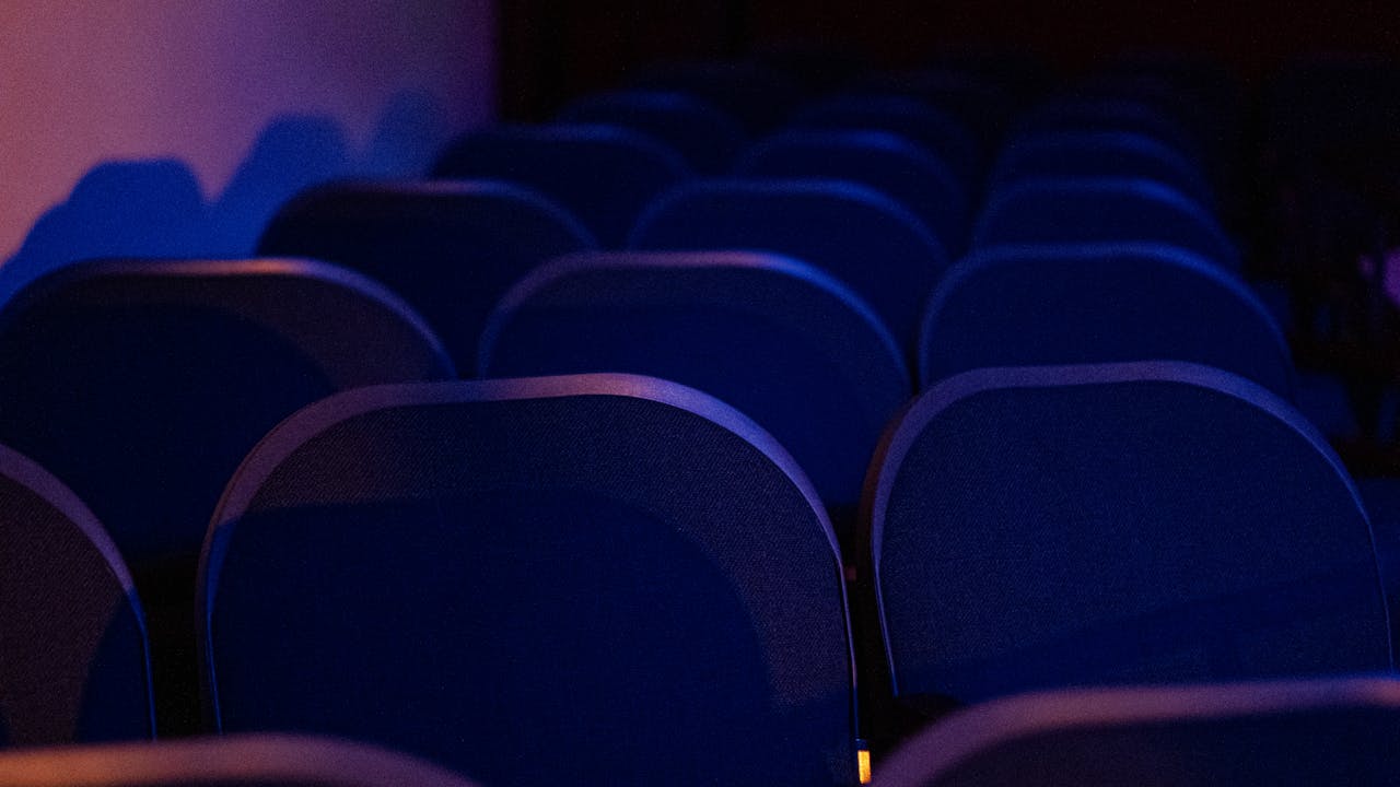 zzzServices Rows of empty theater seats bathed in dark, moody lighting creating a dramatic ambiance.