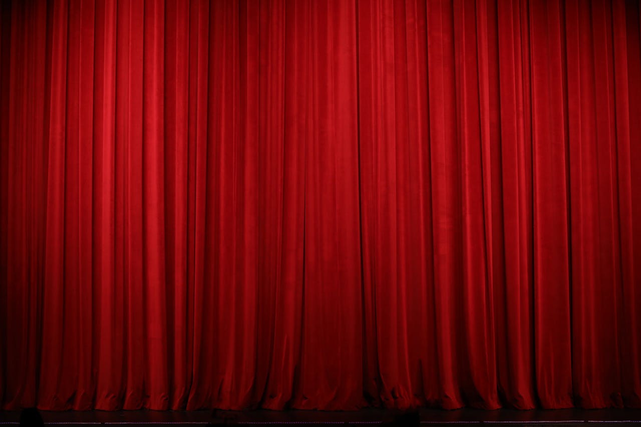 Elegant red theater curtains creating a dramatic stage backdrop indoors.