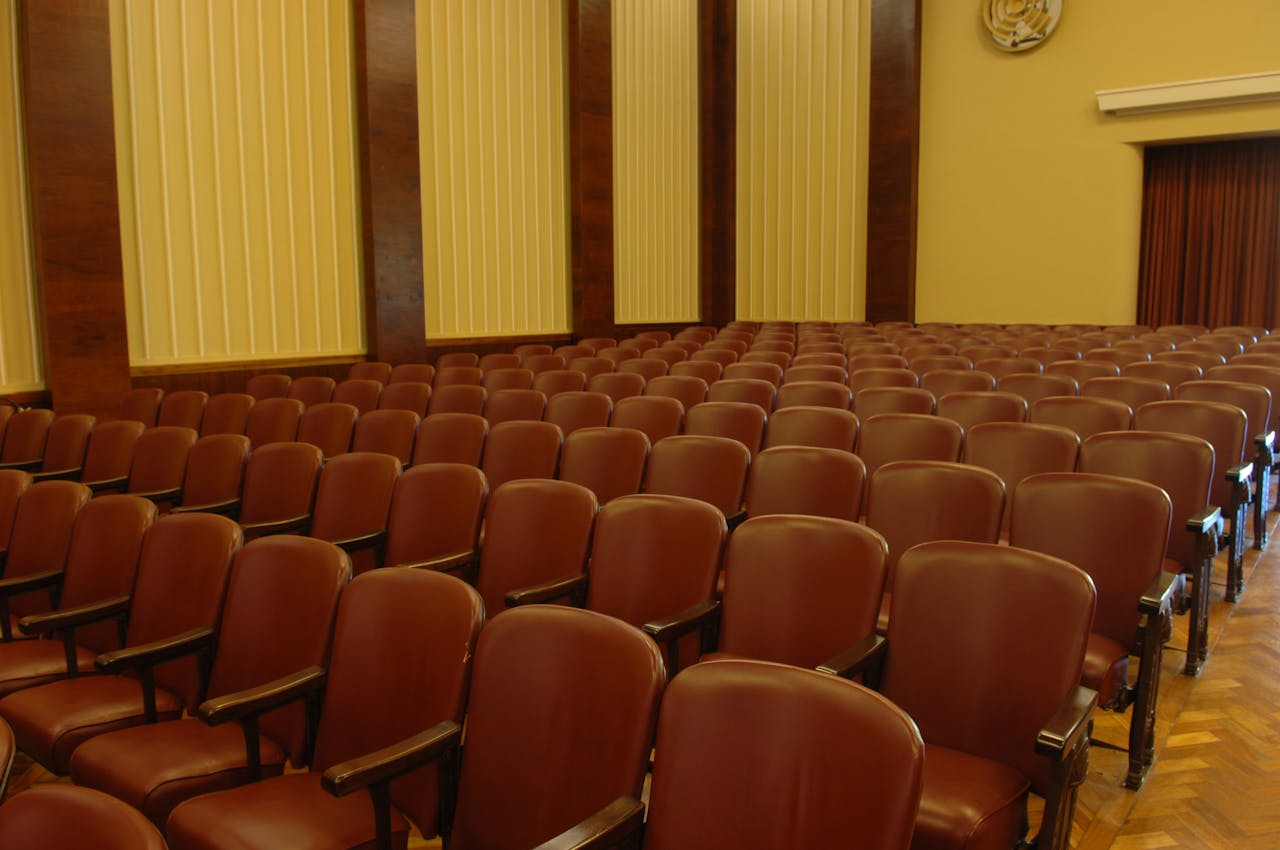 zzzServices An empty auditorium with brown seats and wooden flooring, ideal for events.