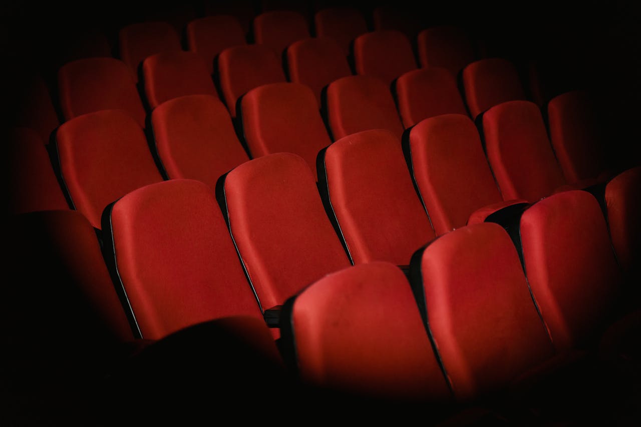 zzzServices Rows of empty red armchairs in a dimly lit cinema setting, creating a moody atmosphere.
